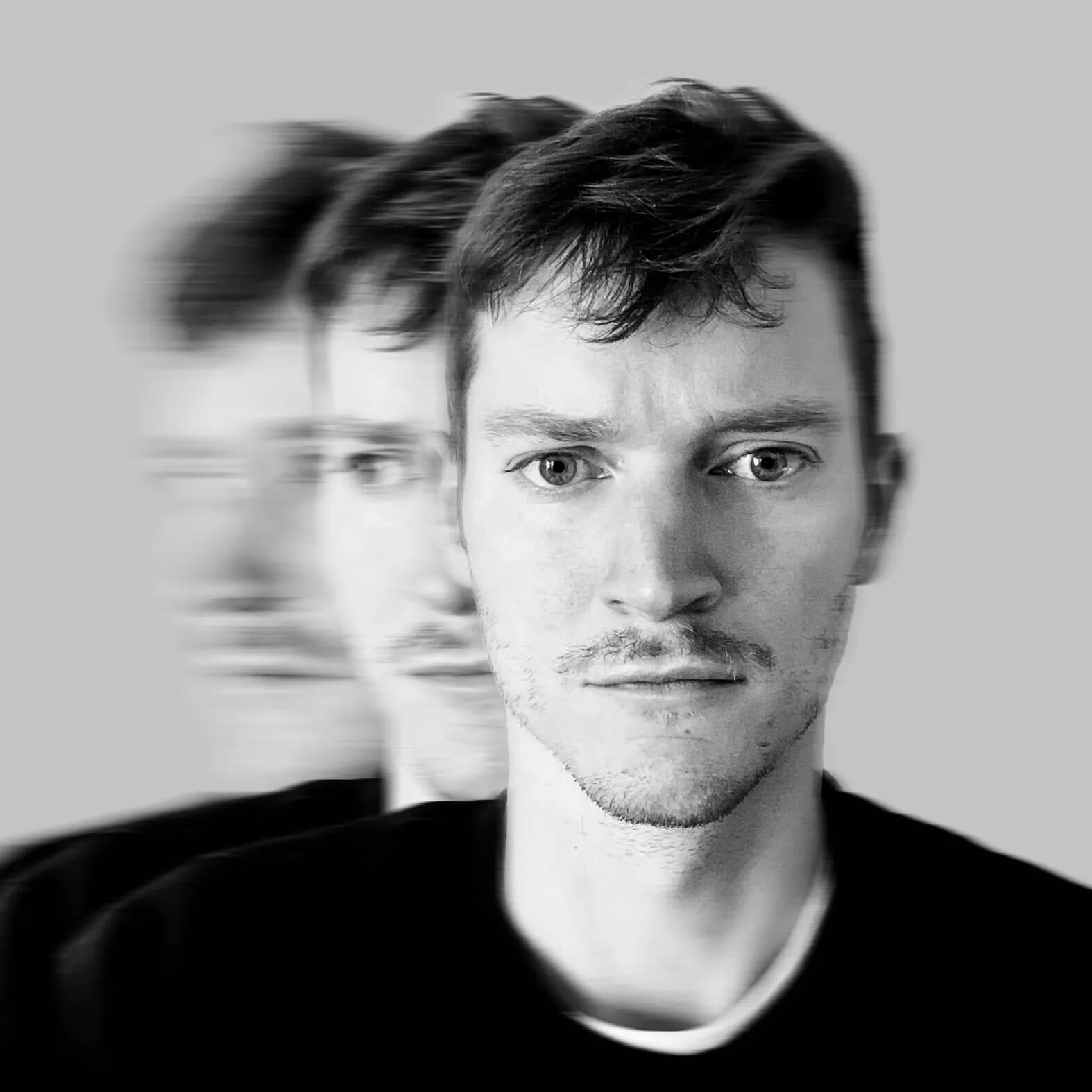 A man with short hair stares forward with a neutral expression. Two blurred, ghost-like copies of his face appear on either side against a plain gray background, evoking the confusion and urgency seen during Operation Outbreak.