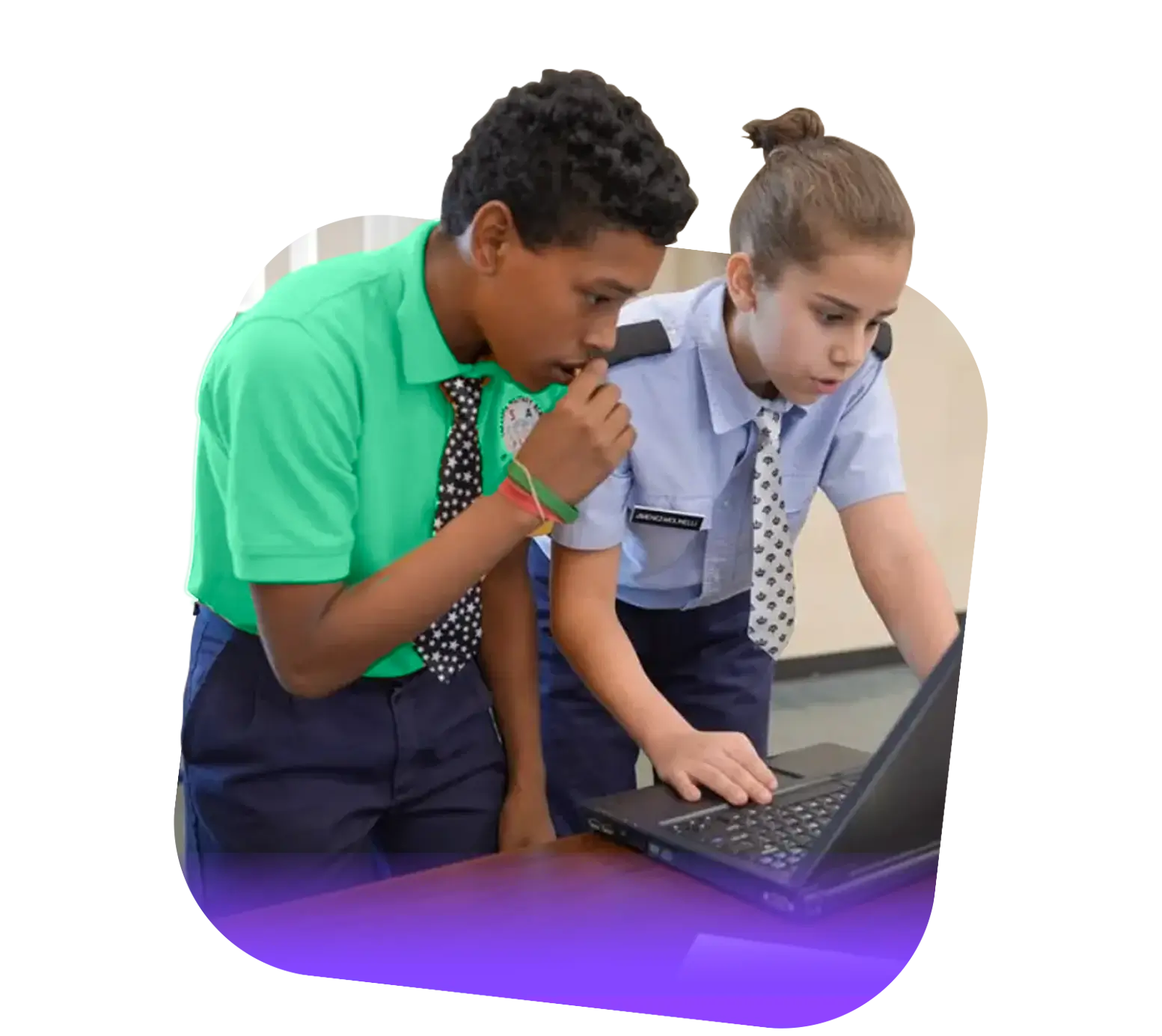 Two students in uniform, one in a green shirt and tie and the other in blue, are intently looking at a laptop together on a table while working on their Operation Outbreak project.