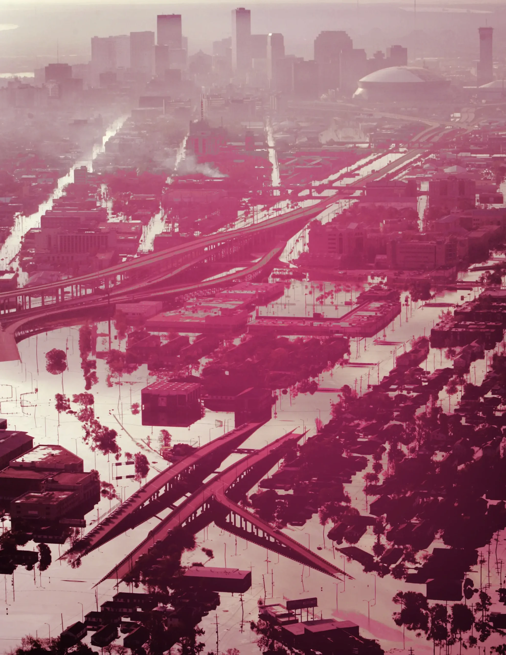 Aerial view of a city with highways and buildings submerged in floodwater, tinted red, suggesting the chaos of an operation outbreak, with the downtown skyline visible through the haze.