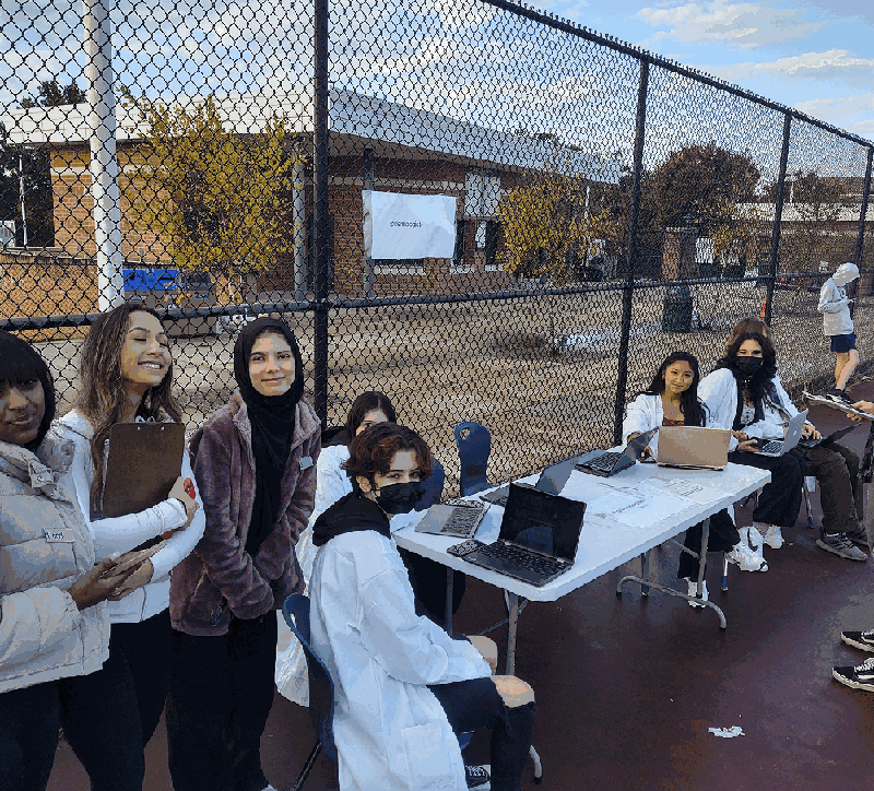 Students staffing an epidemiologists station during a simulation, masked and working at laptops