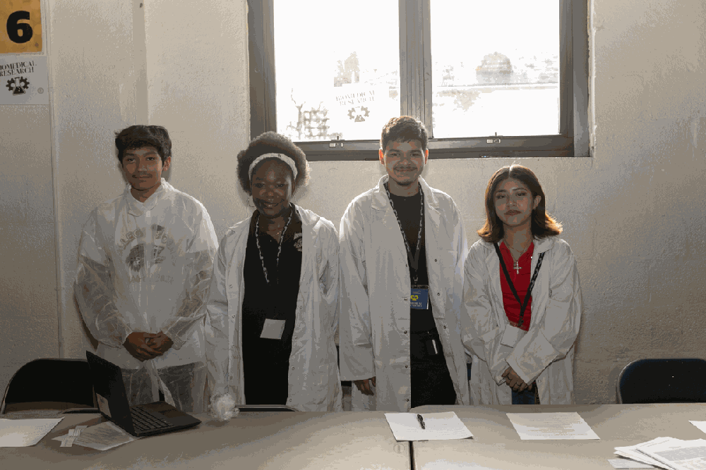 Students working together at a long table during a simulation, some in lab coats